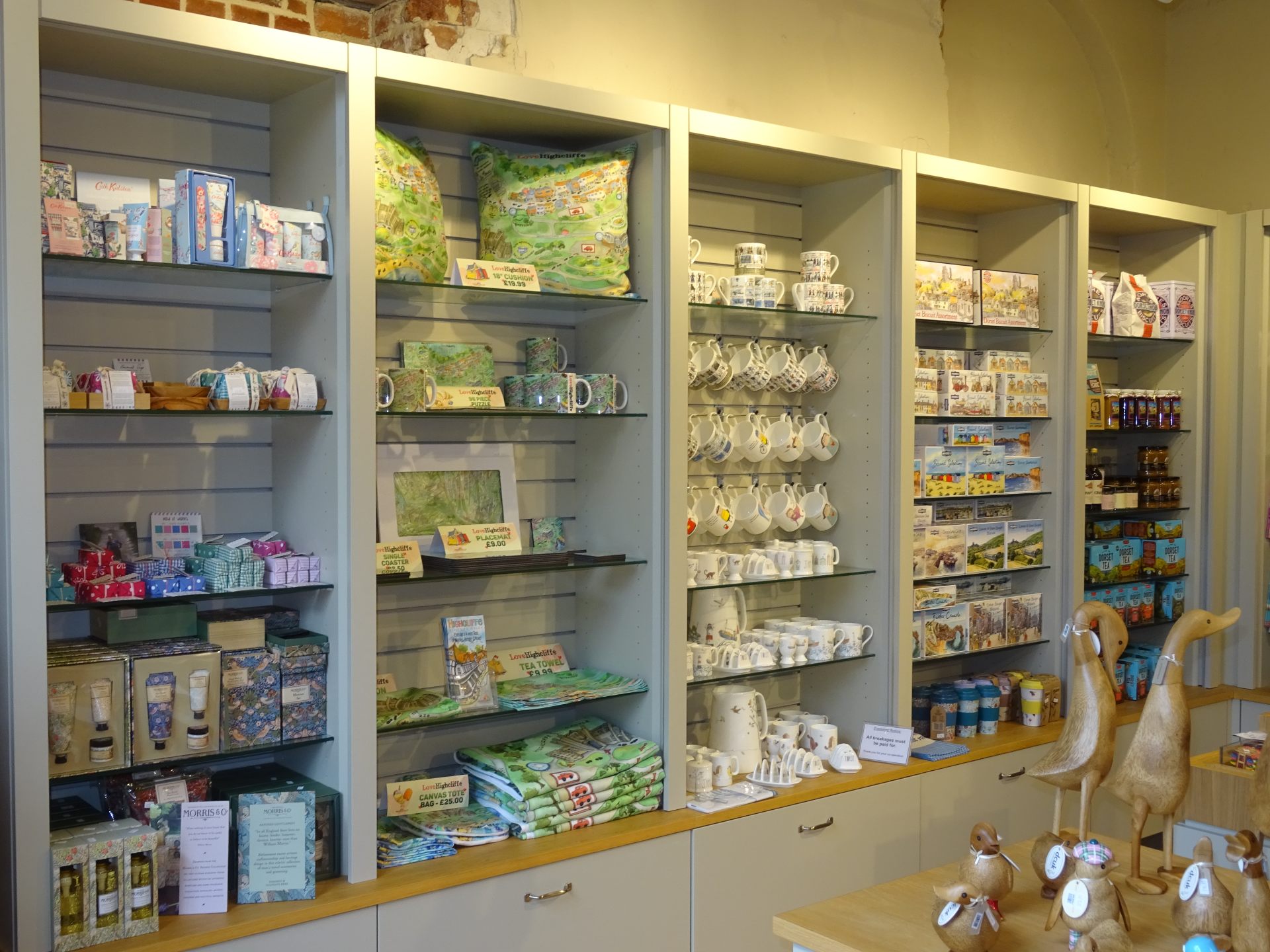 A row of fully stocked shop shelves with an array of gifts such as ceramics, toiletries and local produce.