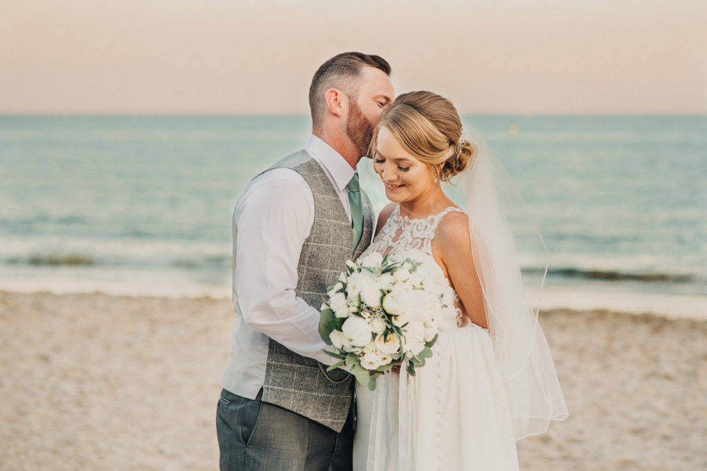 Husband kissing wide on Highcliffe beach during their wedding day