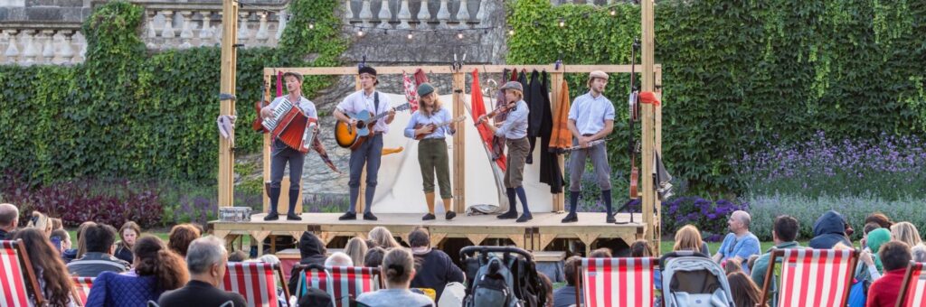 Image of actors on a wooden stage performing outside